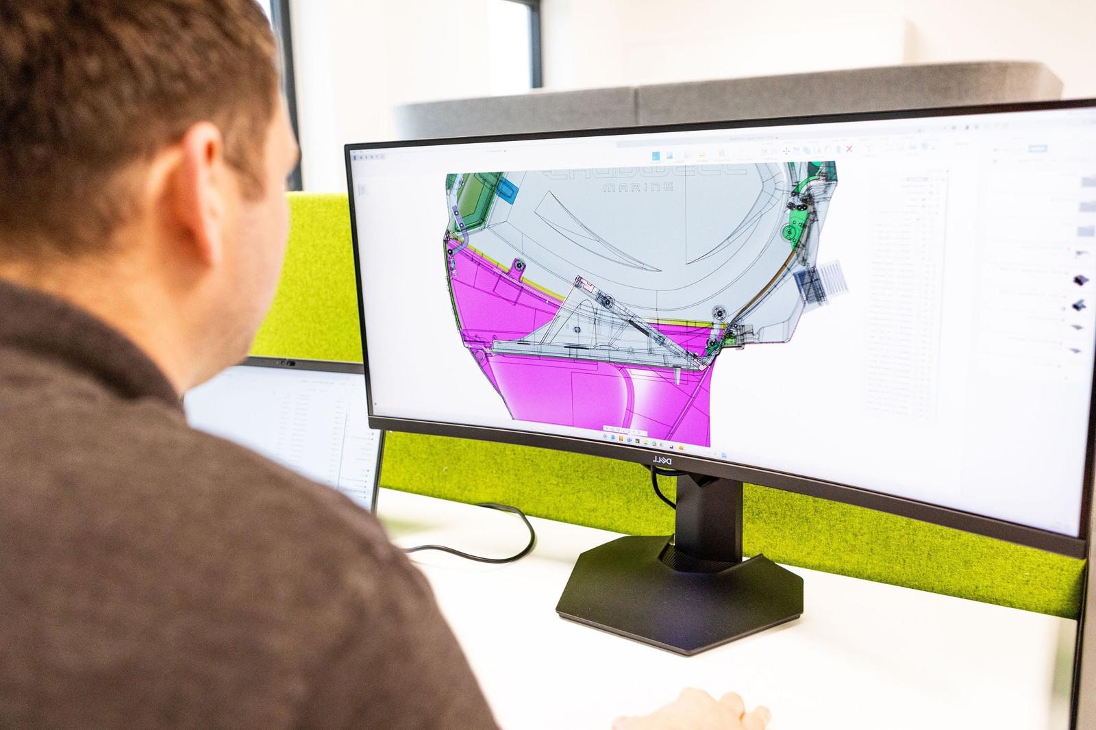 Engineer reviewing a colourful CAD simulation on a monitor
