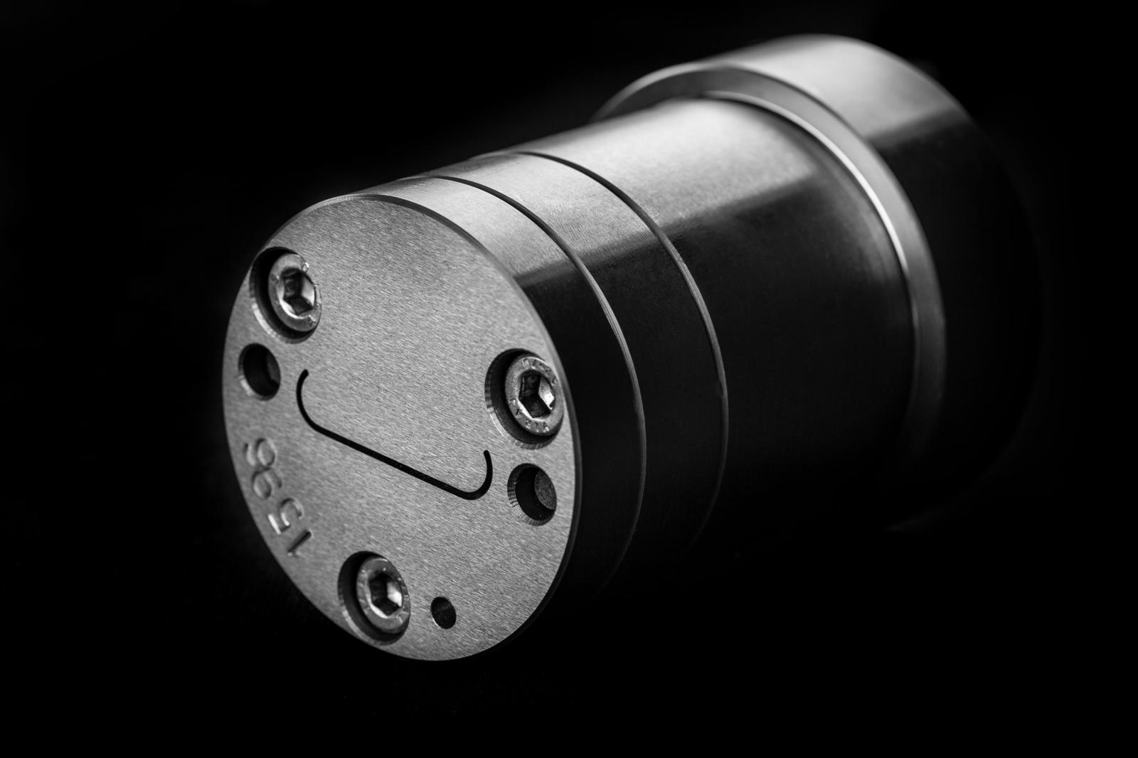 A precision machined cylindrical component held under inspection lighting