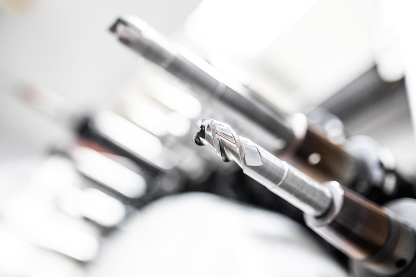 A precision machined metal component held up for inspection in a workshop