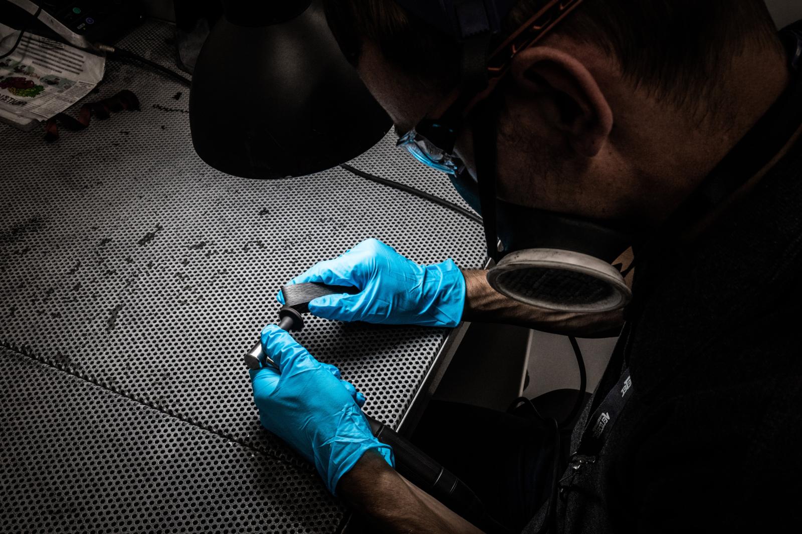 Technician in blue gloves inspecting a component