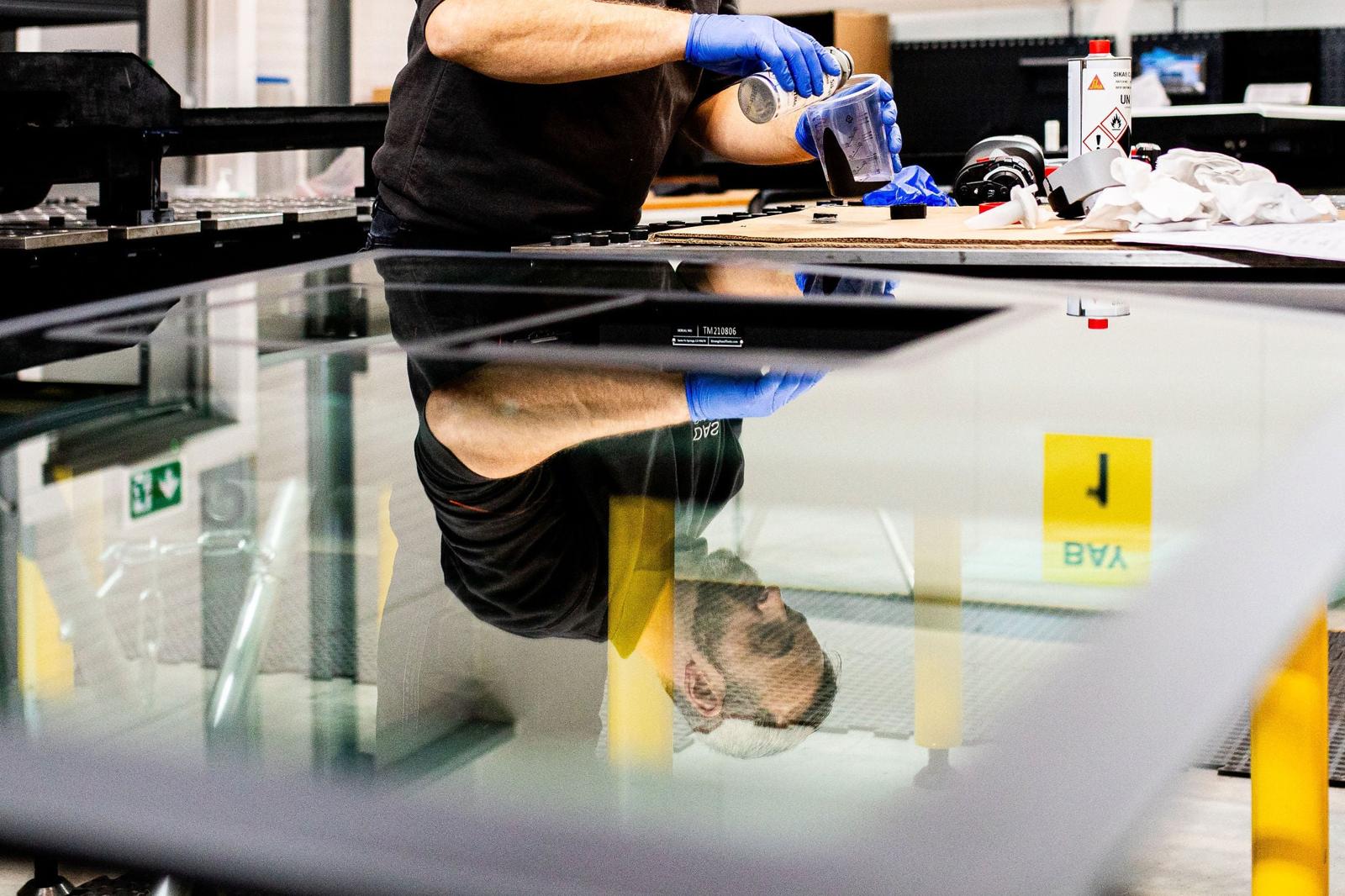 Technician working on a glass panel component in a workshop