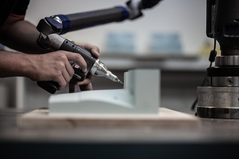 Axiom robotic arm machining a block in a manufacturing cell
