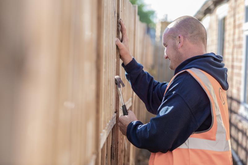 Knight Fencing installer in hi-vis fitting a timber fence