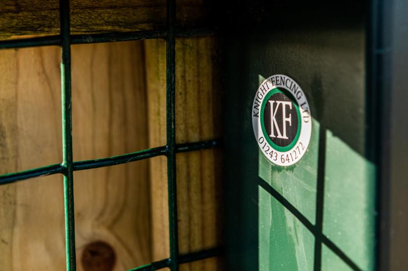 Knight Fencing KF emblem on a green timber gate