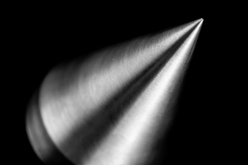 Polished machined metal cone on a black background