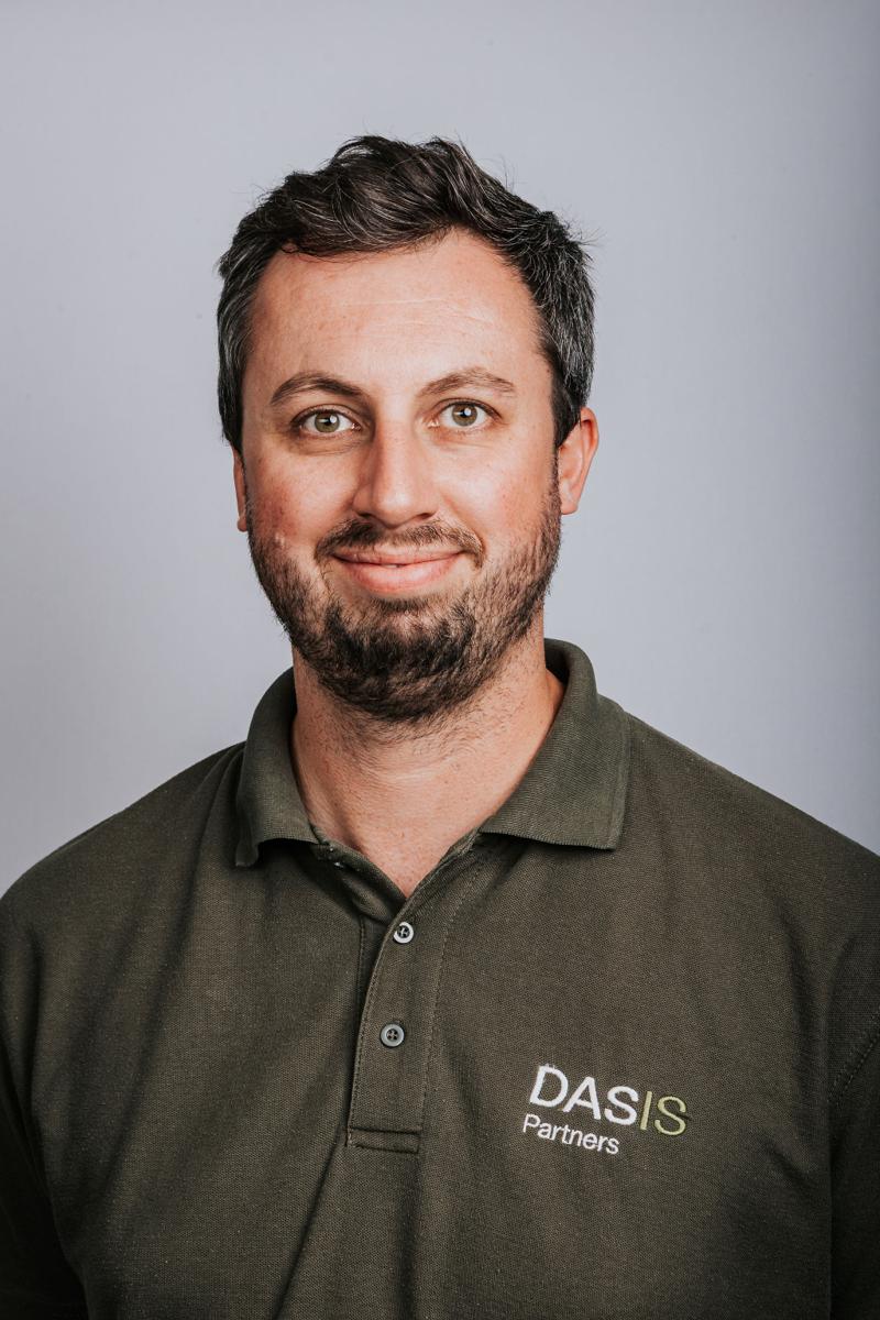 Headshot of a bearded DASIS Partners team member in an olive polo shirt