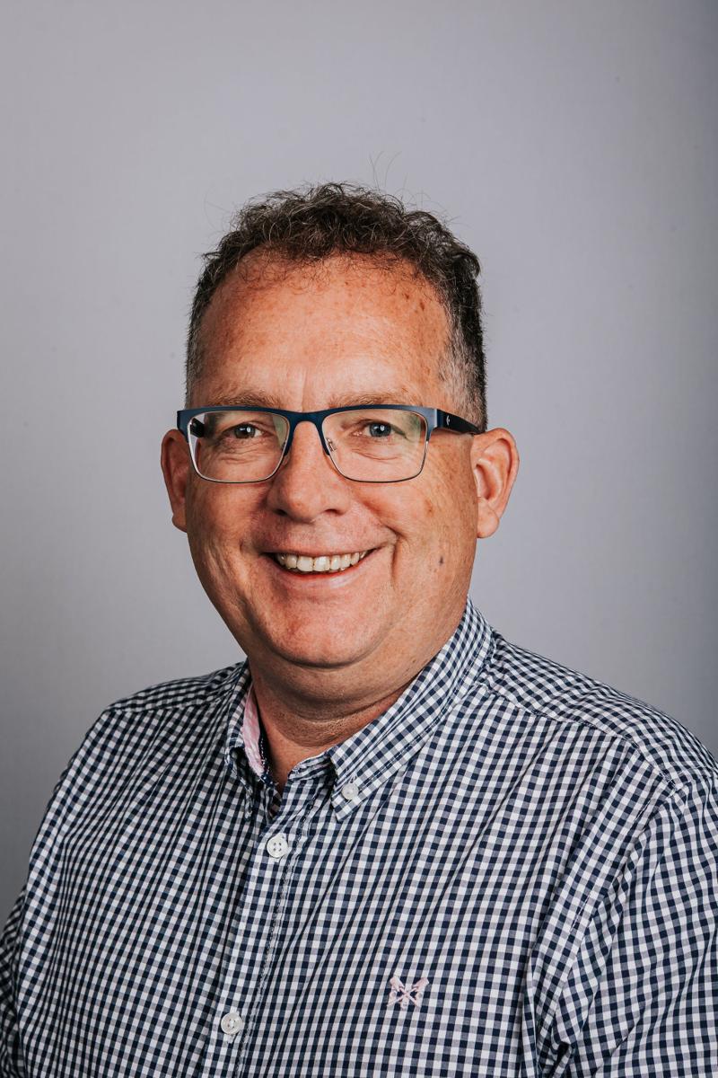 Headshot of a DASIS Partners team member in a checked shirt and glasses