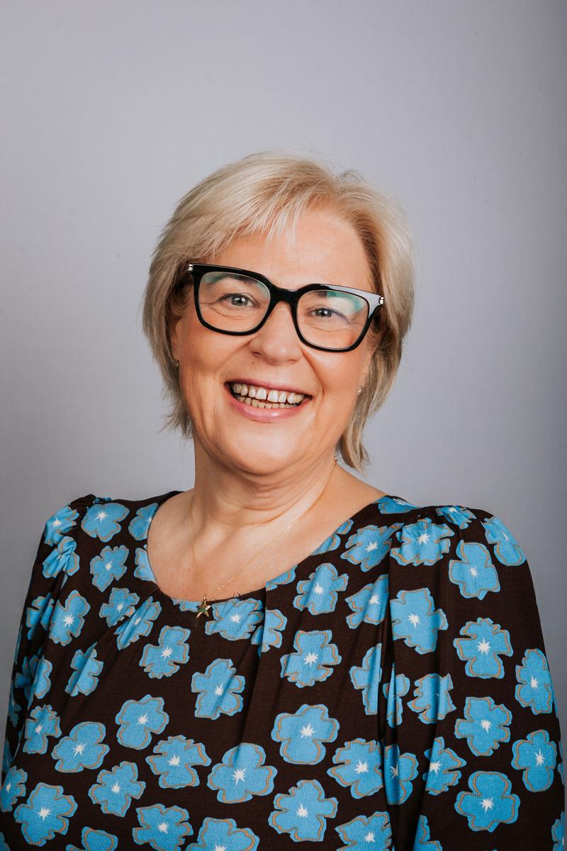 Headshot of a DASIS Partners team member wearing glasses and a floral blouse