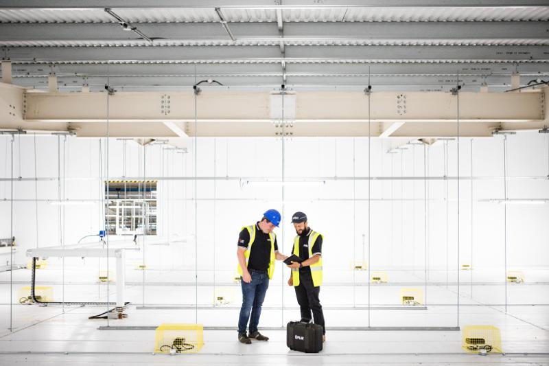 Two engineers in hi-vis and hard hats surveying an empty warehouse