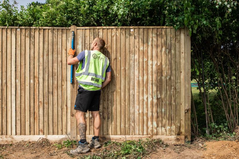 Knight Fencing installer in hi-vis beside a new timber fence