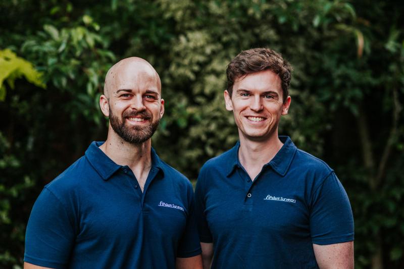 Two Pallant Surveyors team members in branded polos outside a property