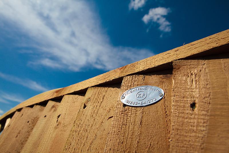 Knight Fencing timber fence panel with a metal plaque against a blue sky
