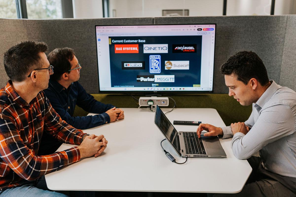 Pallant team reviewing client accreditation logos on a screen during a meeting