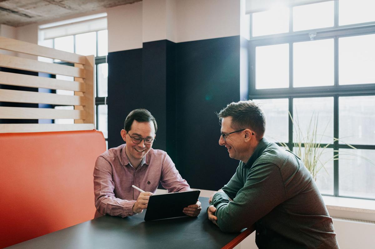 Two Pallant team members working at a desk by the window